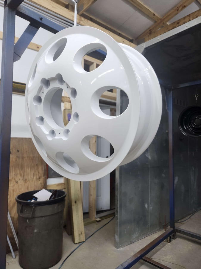 Gloss white wheel hanging in the shop, angled view