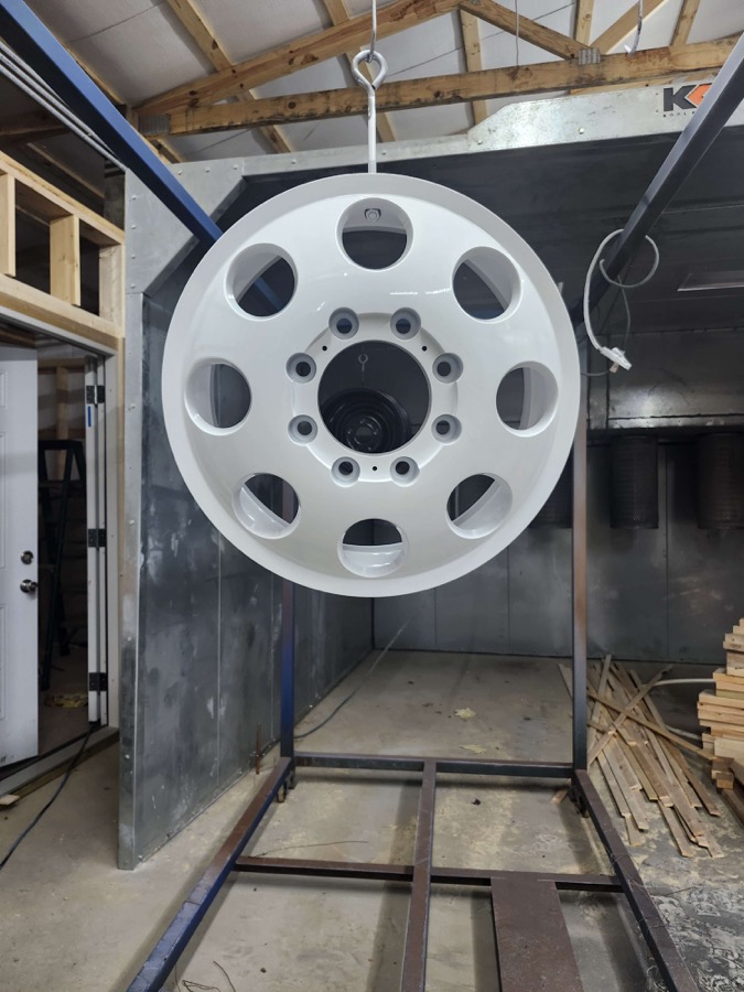 Finished white wheel hanging in the coating shop, front view