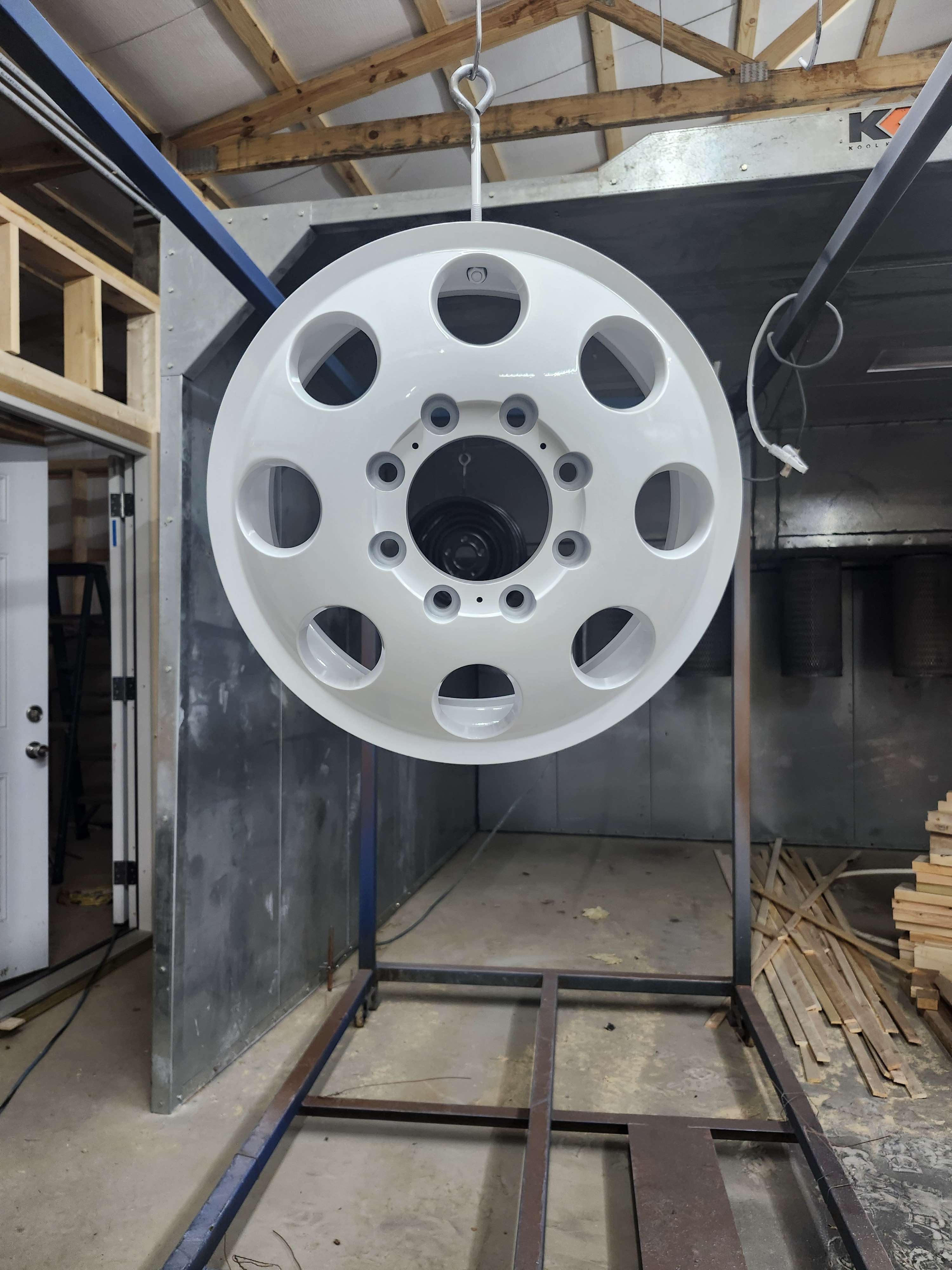 Finished white wheel hanging in the coating shop, front view