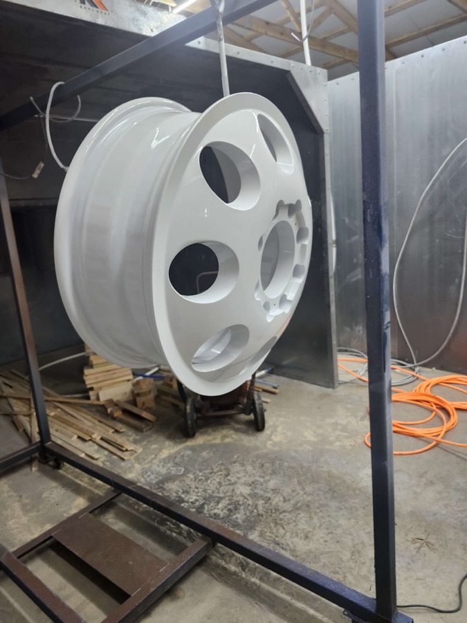 Gloss white wheel hanging from a rack, side angle
