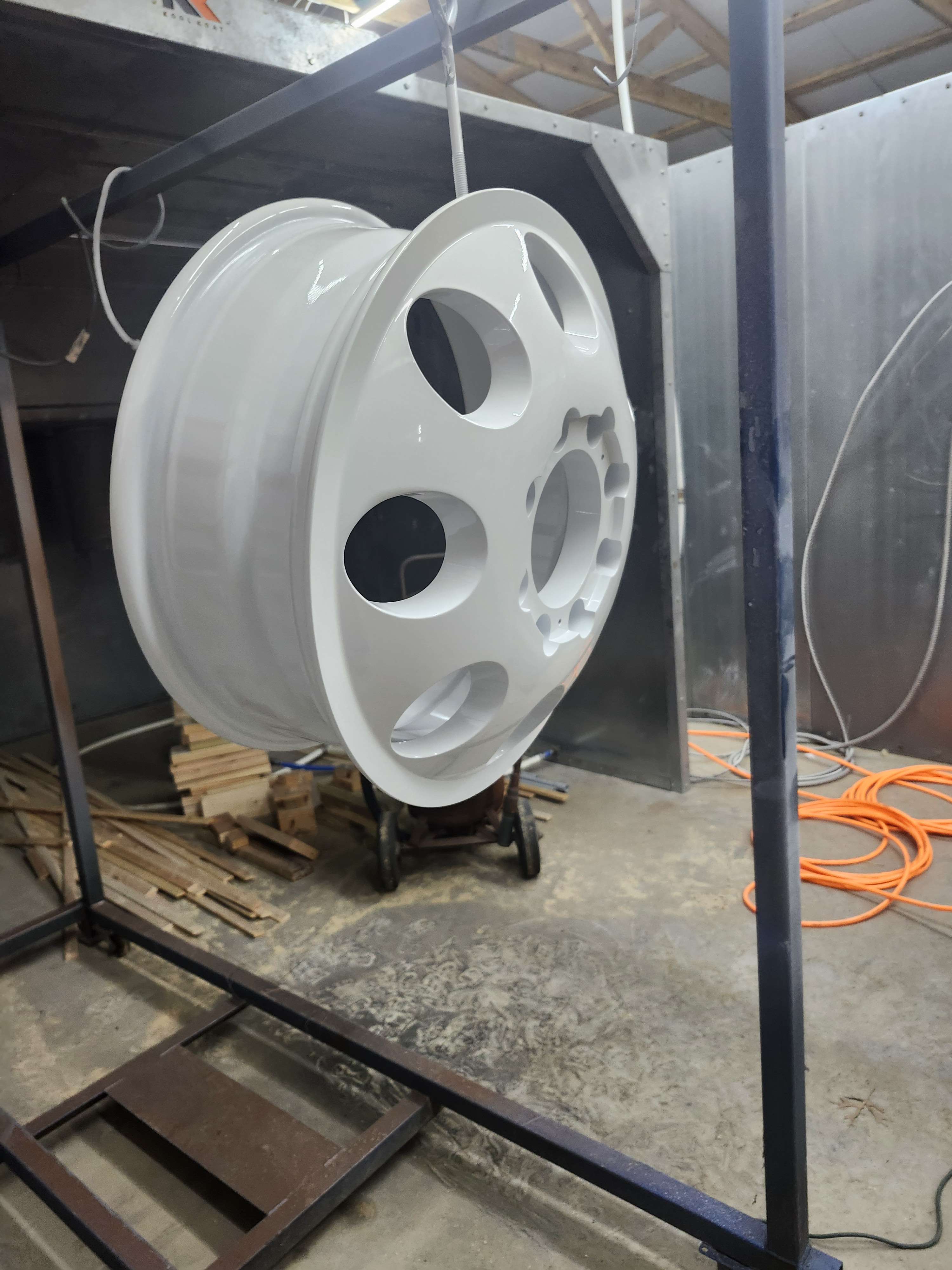 Gloss white wheel hanging from a rack, side angle